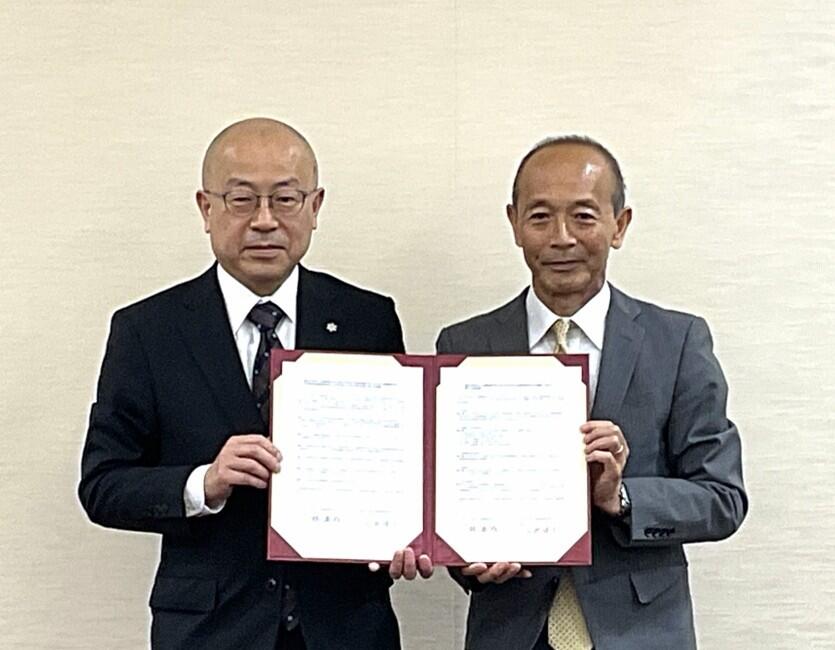 両学長が署名した協定書を持って立っている。記念写真