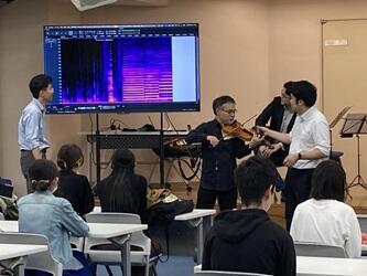 演奏しているヴァイオリンの音の声紋をディスプレイに表示して、本学教員が説明している様子