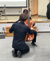 学生がチェロの演奏を体験する様子
