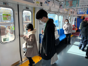 TX列車内で児童がアイマスクをして視覚障害を疑似体験し、列車内を確認する様子