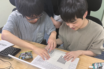 立体コピー用紙に印刷された図を使って、酒寄さんに問題を解説している生田さんの写真